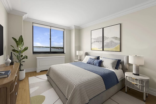 bedroom with light wood-style floors, ornamental molding, and baseboards