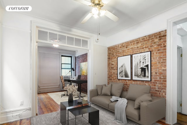 living room with hardwood / wood-style floors, ceiling fan, and brick wall