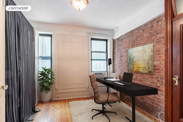 office with brick wall and light hardwood / wood-style flooring