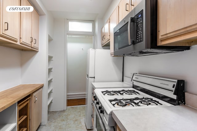 kitchen with range with gas stovetop, stainless steel microwave, and light brown cabinetry