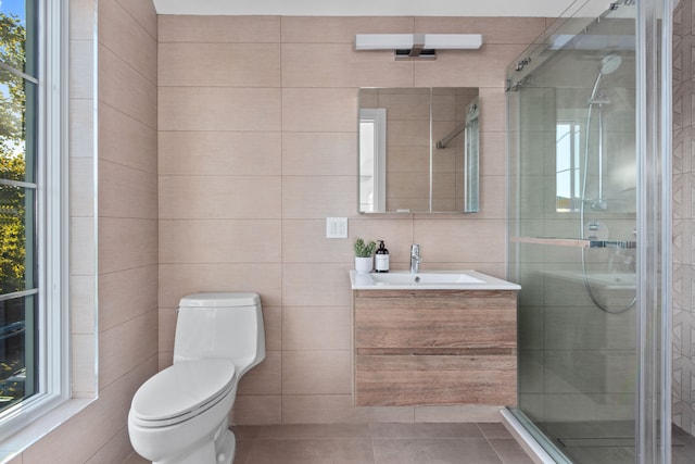 bathroom with tile patterned flooring, tile walls, toilet, a stall shower, and vanity