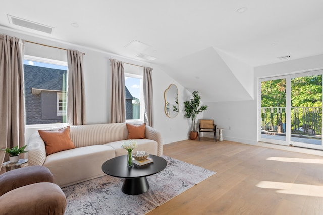 living area featuring vaulted ceiling, visible vents, and light wood-type flooring