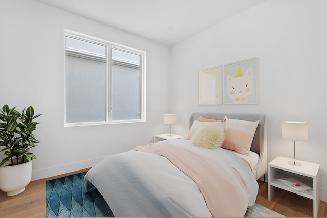 bedroom featuring multiple windows, baseboards, and wood finished floors