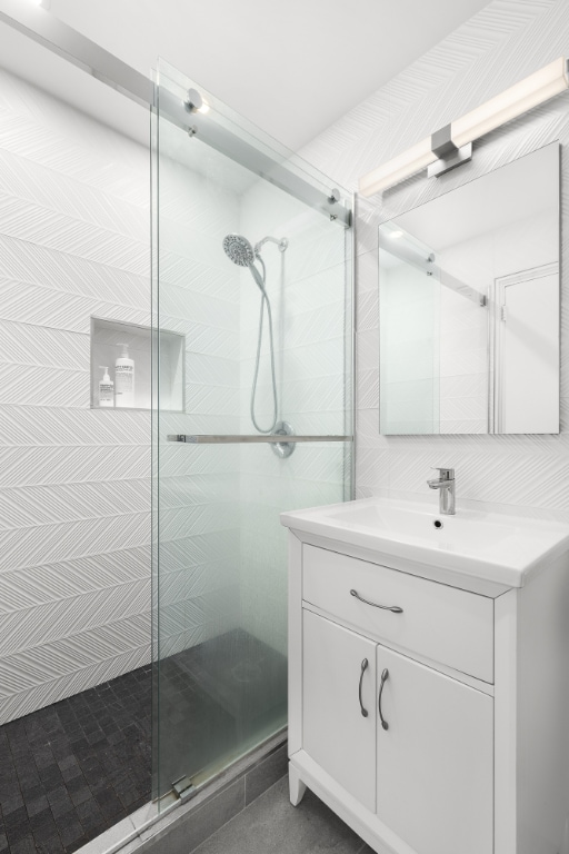 bathroom with a shower with shower door and vanity