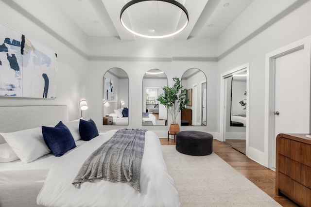 bedroom with a towering ceiling and hardwood / wood-style floors