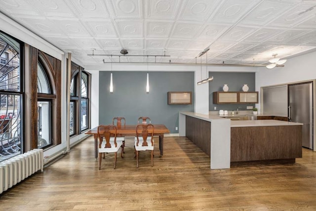 kitchen with hanging light fixtures, hardwood / wood-style flooring, and radiator heating unit