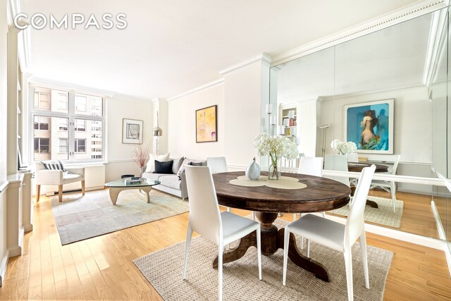 dining space with ornamental molding, light wood-type flooring, and baseboards