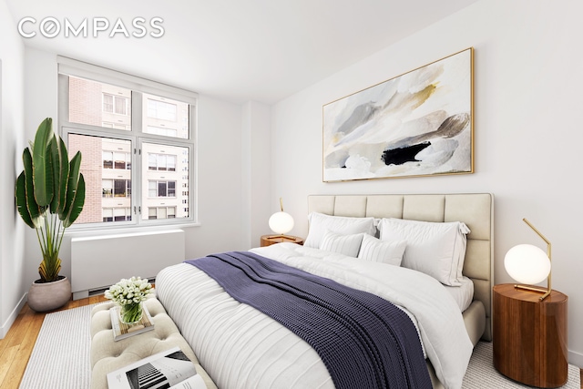 bedroom with radiator, wood finished floors, and baseboards