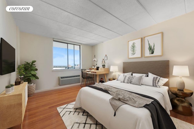 bedroom with hardwood / wood-style flooring, a wall mounted air conditioner, and a textured ceiling