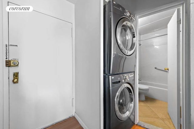 laundry area with stacked washer and clothes dryer and tile patterned floors