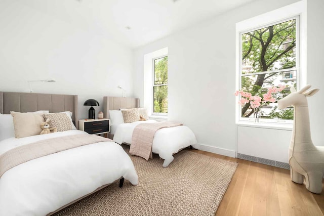 bedroom featuring multiple windows, light wood-type flooring, and baseboards