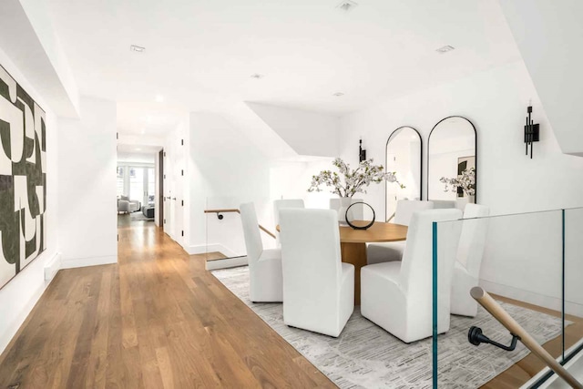 dining area featuring a baseboard radiator, light wood-style flooring, and baseboards