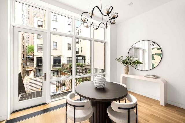 dining room with light wood-type flooring, baseboards, and a notable chandelier