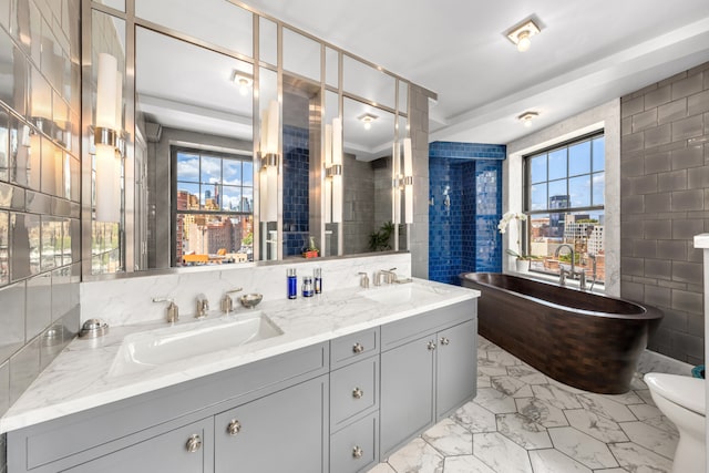 full bath with marble finish floor, a sink, and tile walls