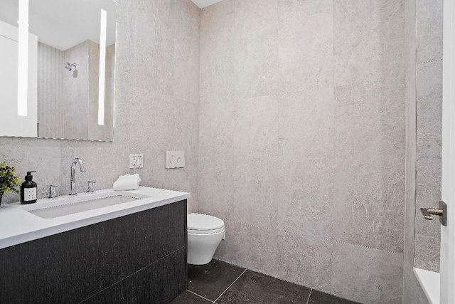 bathroom featuring toilet, vanity, tile patterned flooring, and a shower