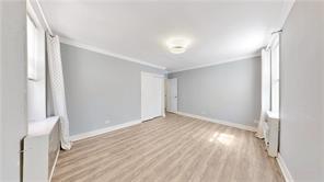 unfurnished bedroom with ornamental molding, light wood-type flooring, and baseboards