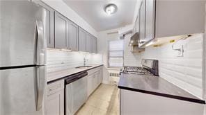 kitchen with under cabinet range hood, tasteful backsplash, appliances with stainless steel finishes, and a sink