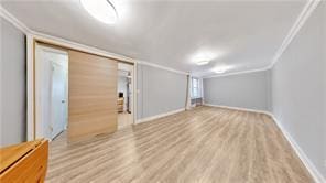unfurnished living room with crown molding, wood finished floors, and baseboards