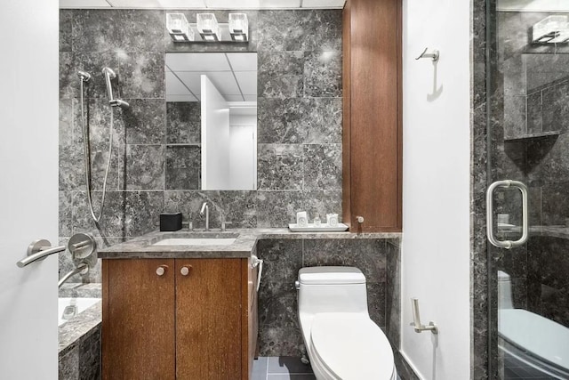 bathroom featuring walk in shower, tile patterned floors, toilet, tile walls, and vanity