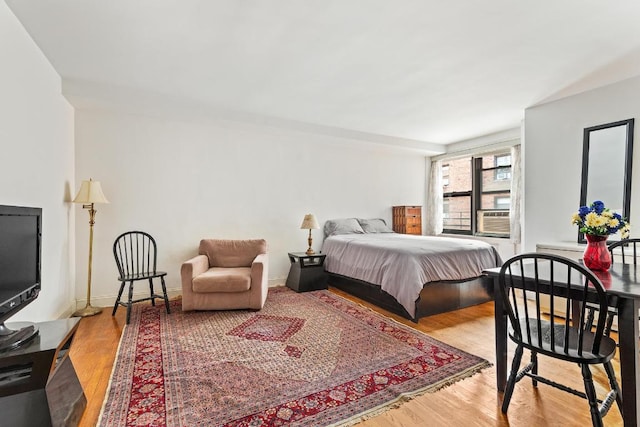 bedroom with cooling unit and light hardwood / wood-style flooring