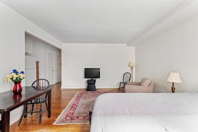 bedroom with wood-type flooring and white fridge