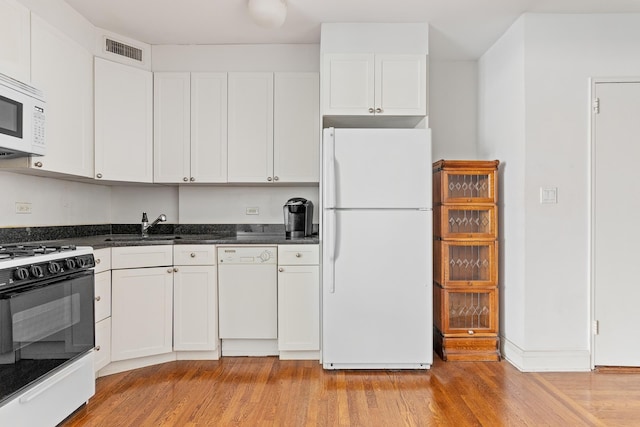 kitchen featuring white appliances, visible vents, white cabinetry, and a sink