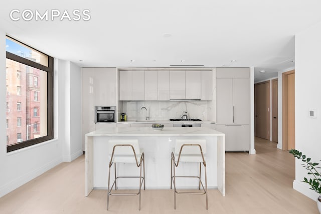 kitchen featuring a sink, a kitchen breakfast bar, modern cabinets, and stainless steel oven