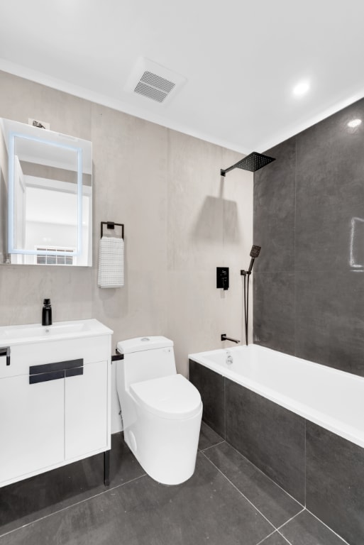 full bathroom with vanity, tiled shower / bath combo, tile patterned floors, and toilet