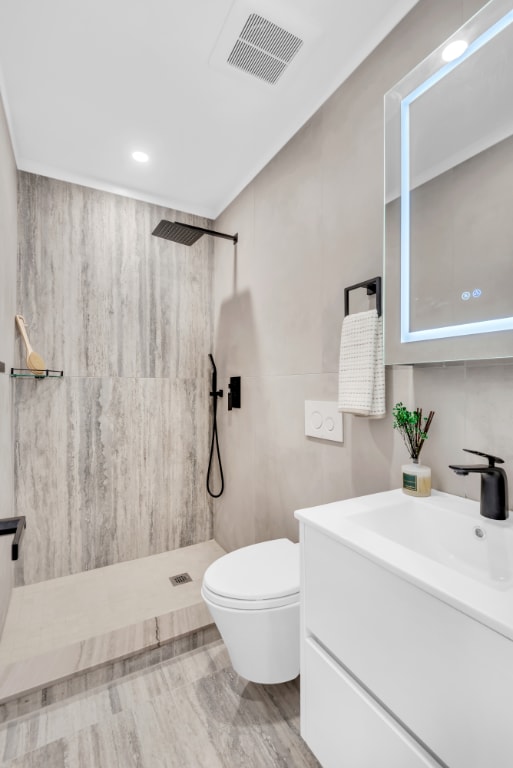 bathroom with hardwood / wood-style flooring, vanity, toilet, and a shower