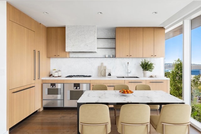 kitchen with stainless steel oven, gas stovetop, light countertops, and a sink