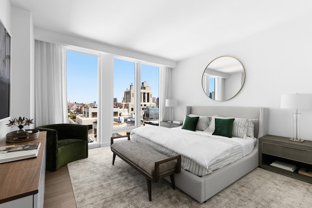 bedroom featuring access to outside, wood finished floors, and a city view