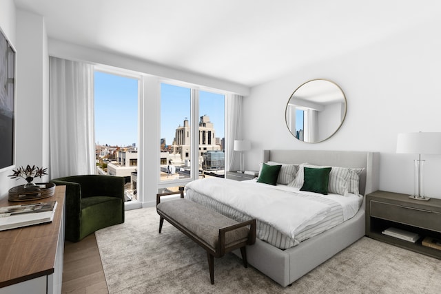 bedroom with a view of city, access to outside, and wood finished floors
