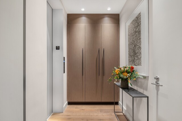 corridor with elevator, light wood-style flooring, and recessed lighting