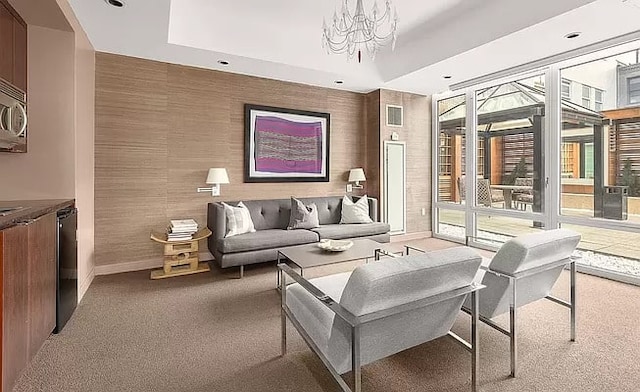 carpeted living room with a tray ceiling and a chandelier