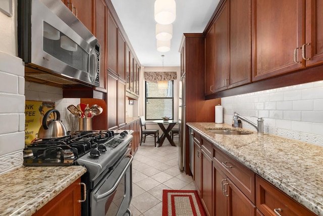 kitchen with appliances with stainless steel finishes, pendant lighting, tasteful backsplash, and sink