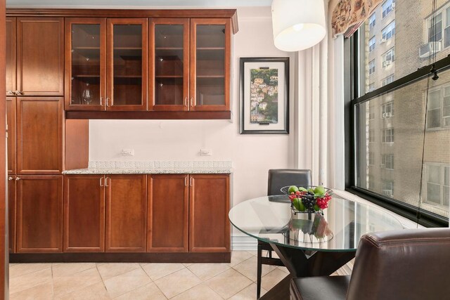 bar with light tile patterned floors and light stone countertops