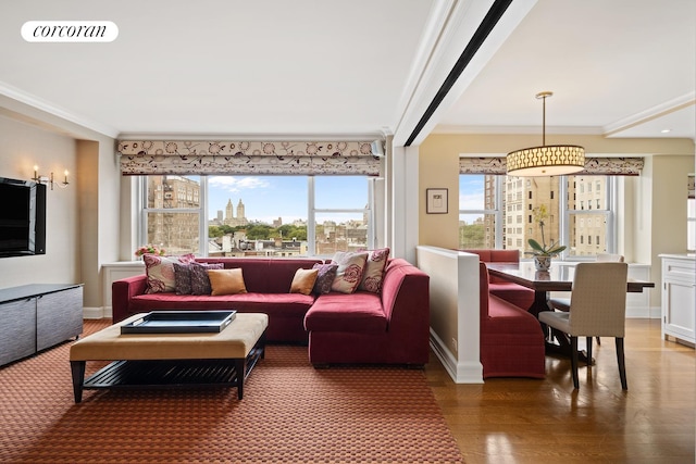 living area with ornamental molding, wood finished floors, visible vents, and baseboards