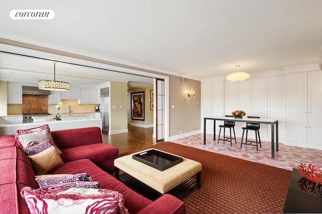 living area with baseboards, visible vents, and ornamental molding