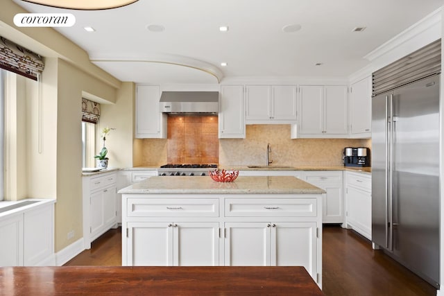 kitchen featuring stainless steel appliances, a sink, visible vents, white cabinetry, and wall chimney exhaust hood