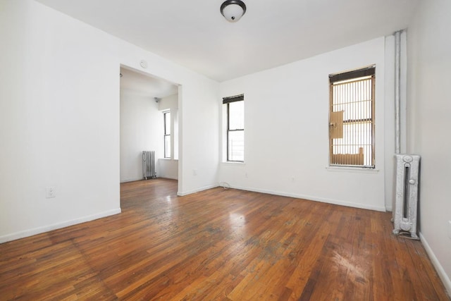 unfurnished room with radiator heating unit and dark hardwood / wood-style floors