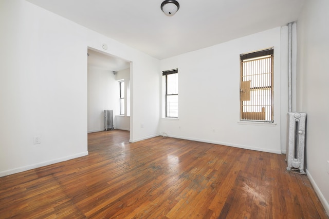 empty room featuring radiator, baseboards, and wood-type flooring