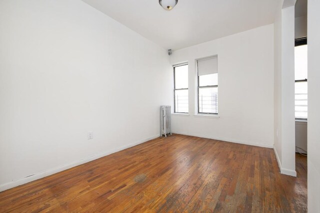 spare room with radiator, dark wood-type flooring, and plenty of natural light