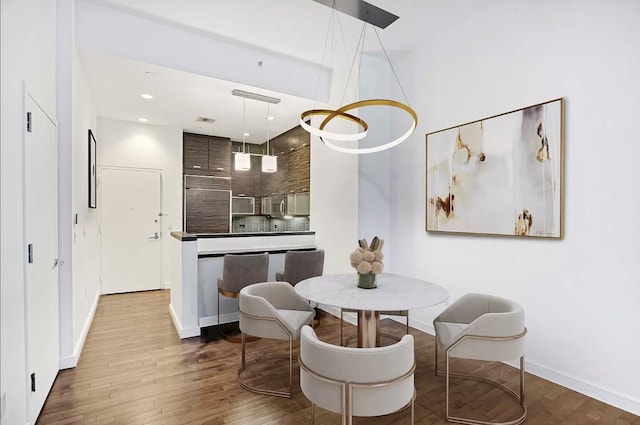 dining area with visible vents, baseboards, and wood finished floors