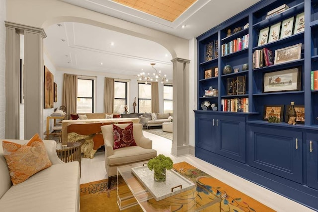 living area featuring ornate columns, arched walkways, a wealth of natural light, and an inviting chandelier