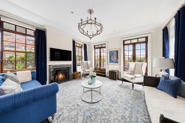 living room with a high end fireplace, a notable chandelier, french doors, and crown molding