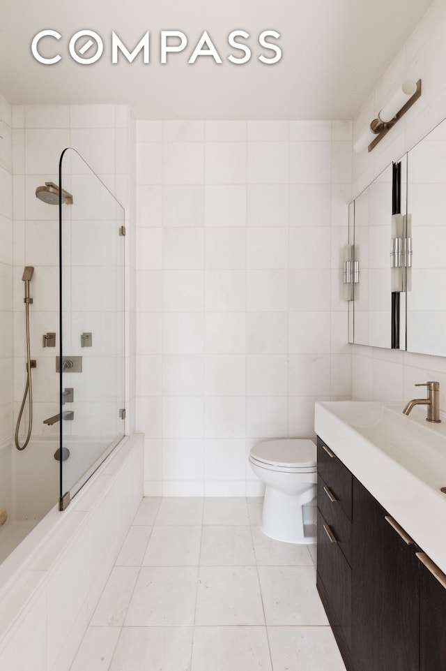 full bathroom featuring tile patterned flooring, vanity, toilet, tile walls, and tiled shower / bath combo