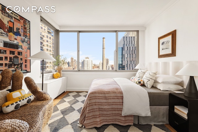 bedroom with wood finished floors, a city view, and ornamental molding