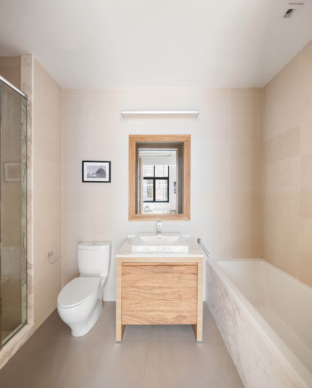 full bath featuring tile patterned floors, a stall shower, tile walls, a bath, and vanity