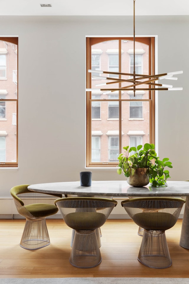 interior space with a healthy amount of sunlight, an inviting chandelier, and wood finished floors