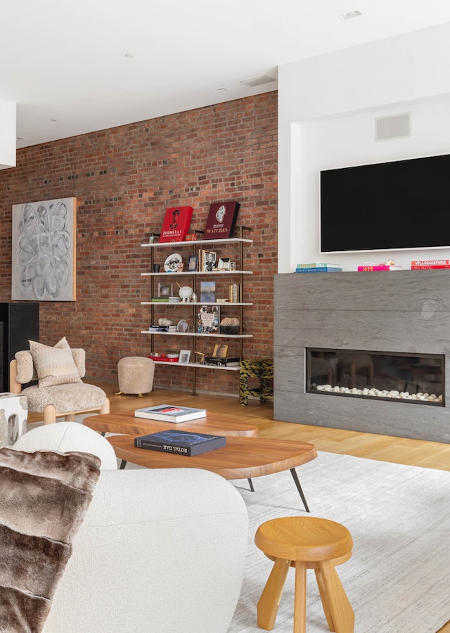 55 Warren St Unit 3, New York City, NY 10007 - living area featuring a glass covered fireplace, wood finished floors, and brick wall